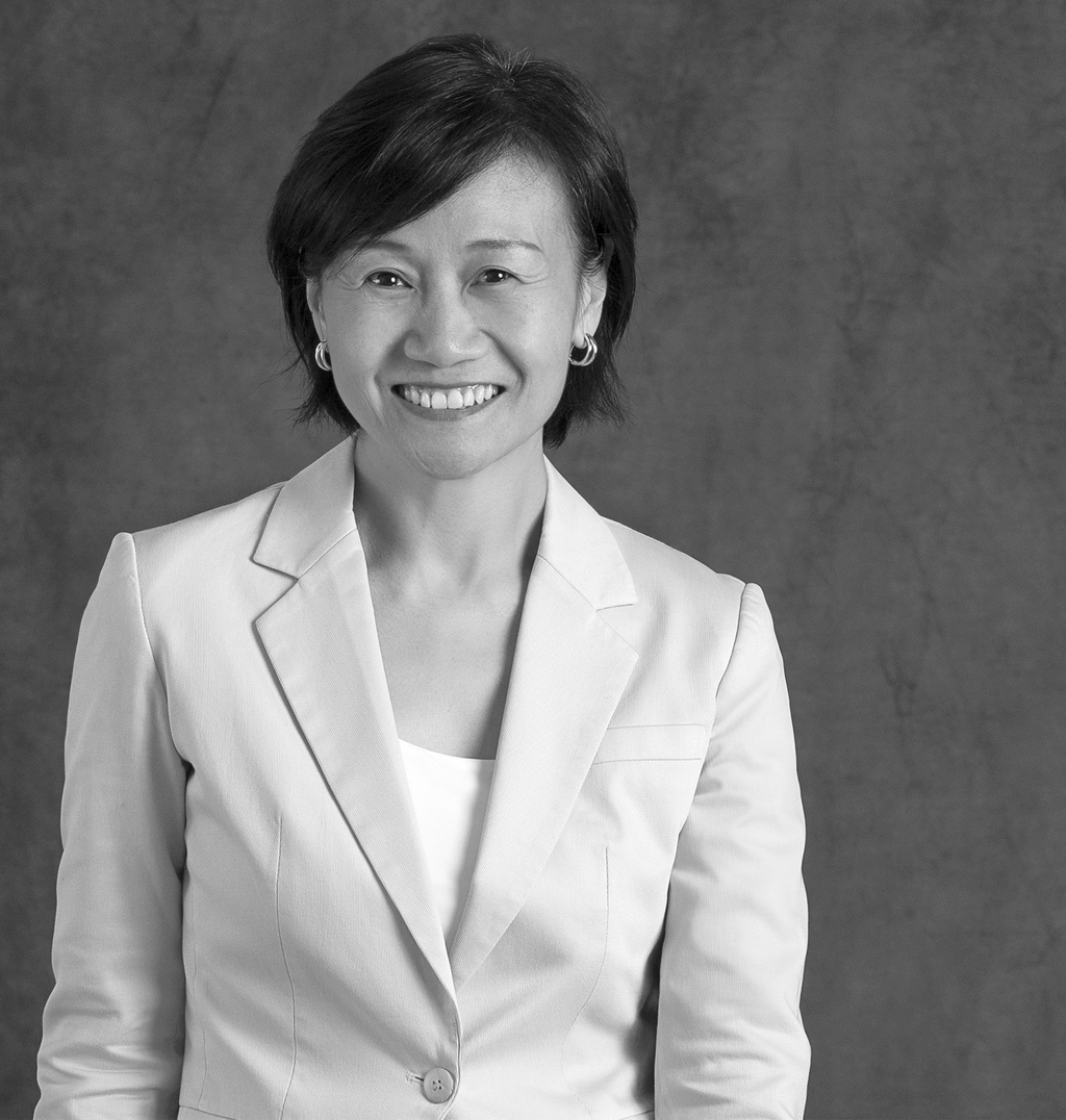 Black and white portrait of Christine Chung, WATG, smiling against a grey backdrop.