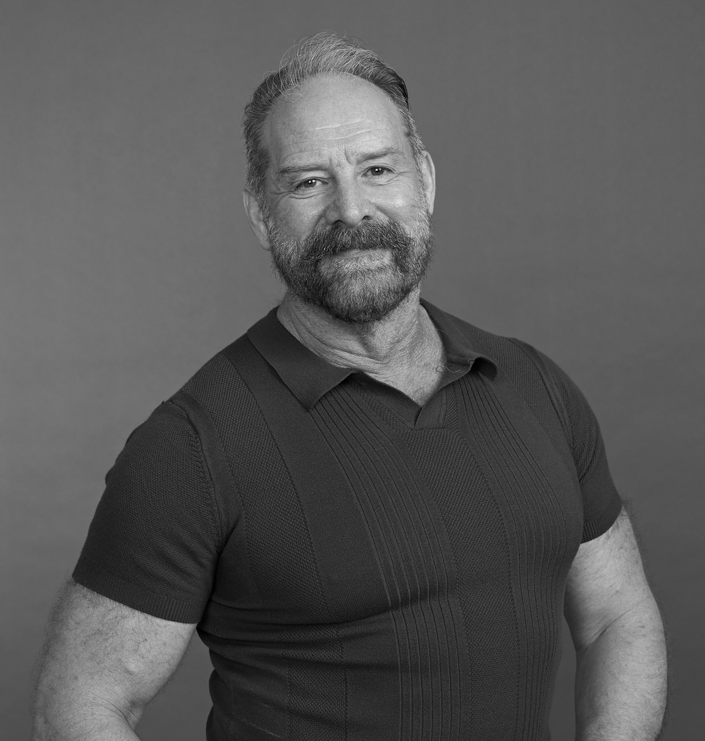 Black and white portrait of Gary Broeker, WATG, smiling against a grey backdrop.