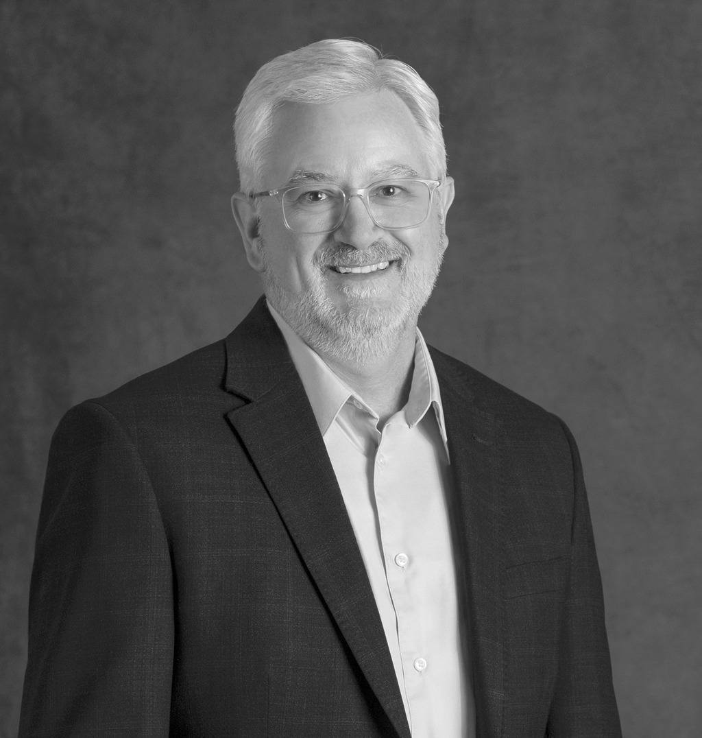Black and white portrait of Mark Petrella, WATG, smiling against a grey backdrop.
