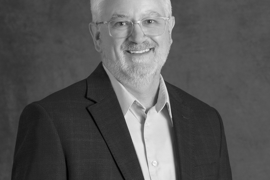 Black and white portrait of Mark Petrella, WATG, smiling against a grey backdrop.