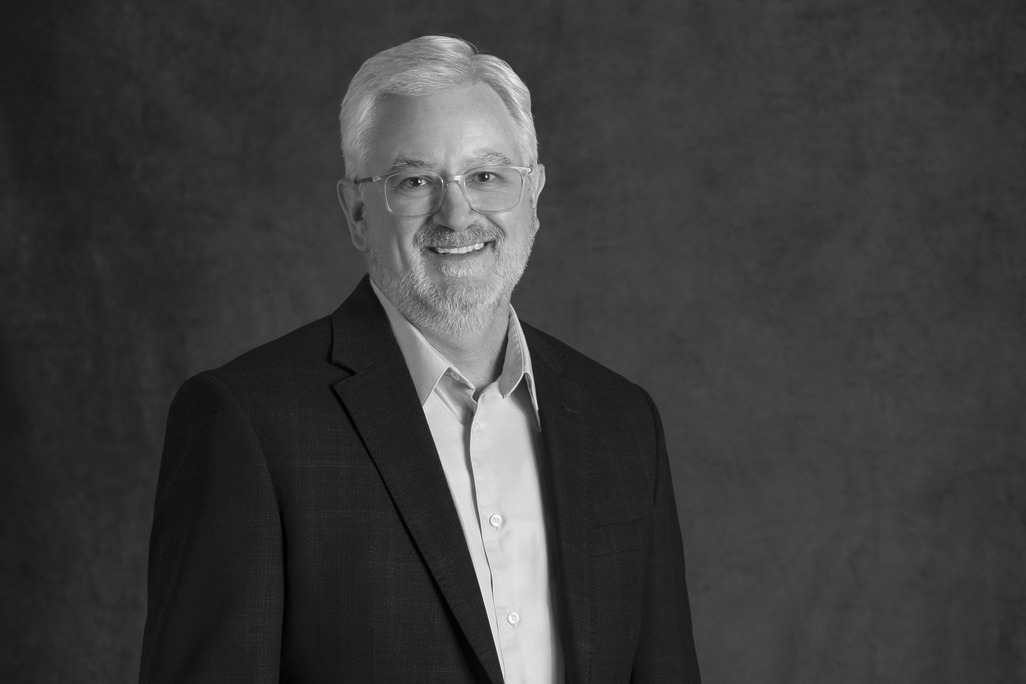Black and white portrait of Mark Petrella, WATG, smiling against a grey backdrop.