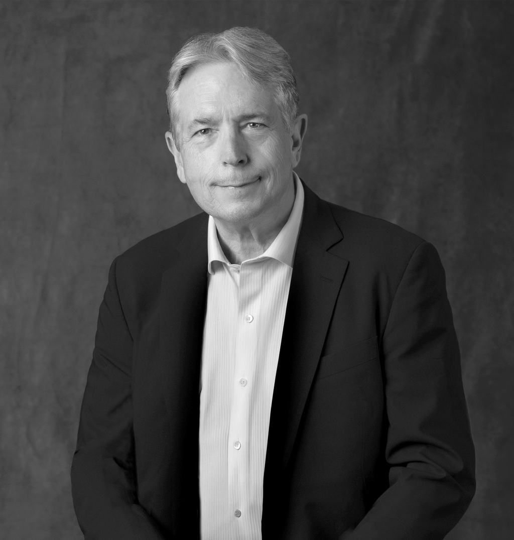 Black and white portrait of Chris Dunn, WATG, smiling against a grey backdrop.