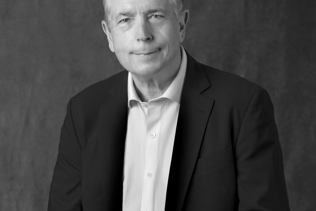 Black and white portrait of Chris Dunn, WATG, smiling against a grey backdrop.
