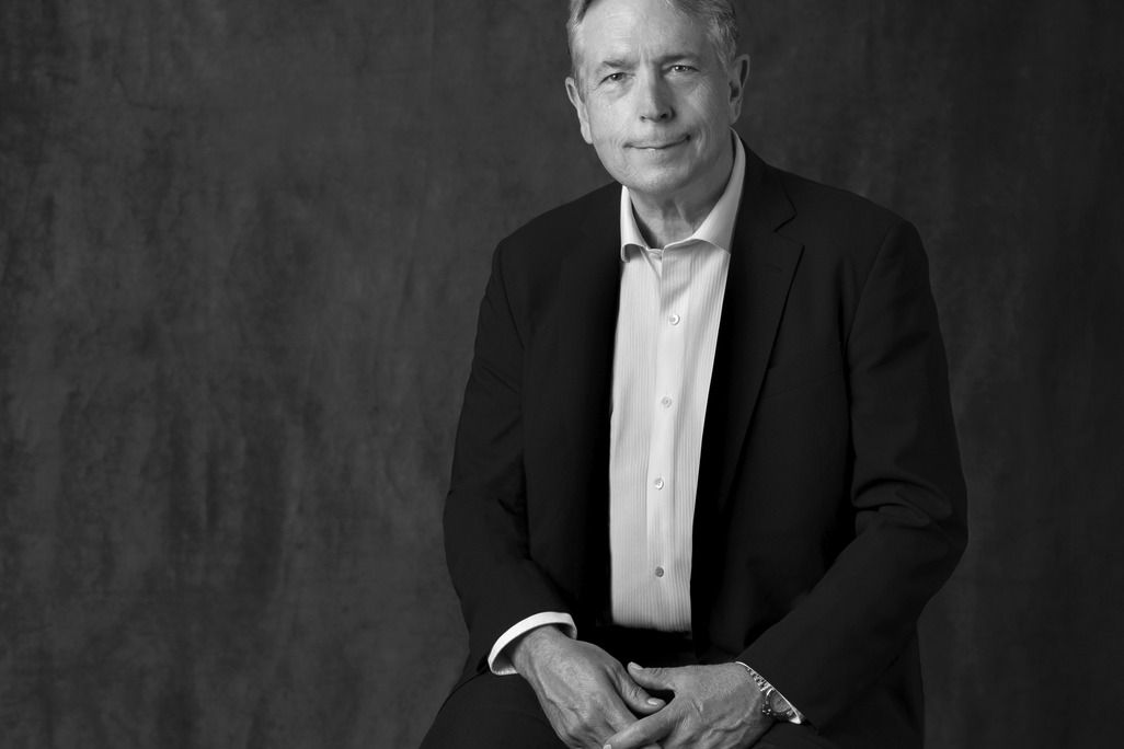 Black and white portrait of Chris Dunn, WATG, smiling against a grey backdrop.