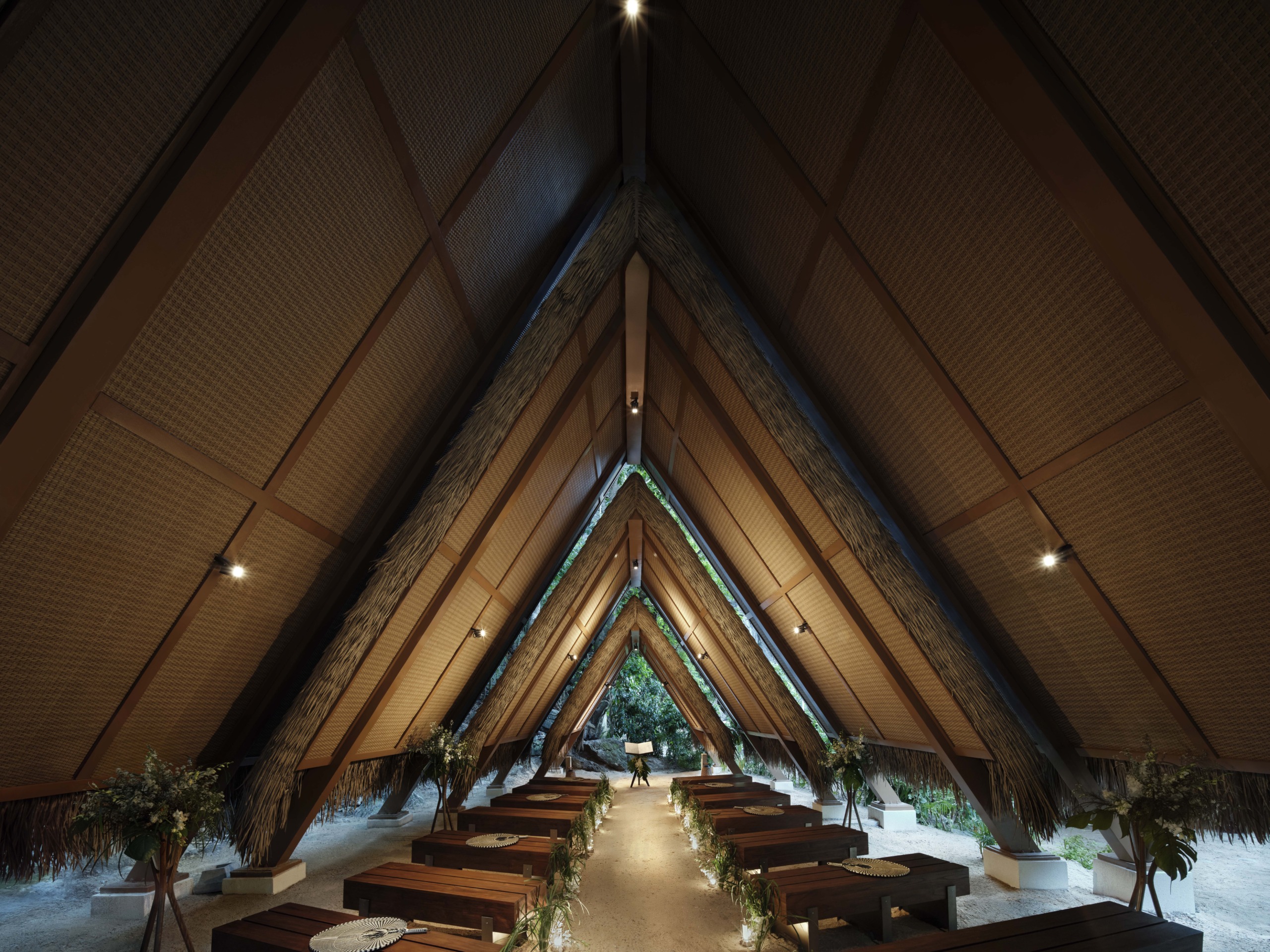 A stunning architectural view of the resort chapel, utilizing a rhythmic A-frame structure with traditional thatching to create a sacred, light-filled space in the forest