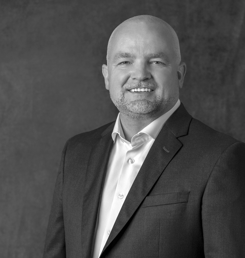 Black and white portrait of Dan Patton, WATG, smiling against a grey backdrop.