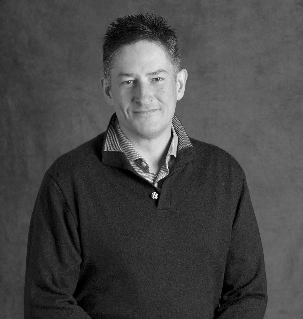 Black and white portrait of Ashley Scott, WATG, smiling against a grey backdrop.