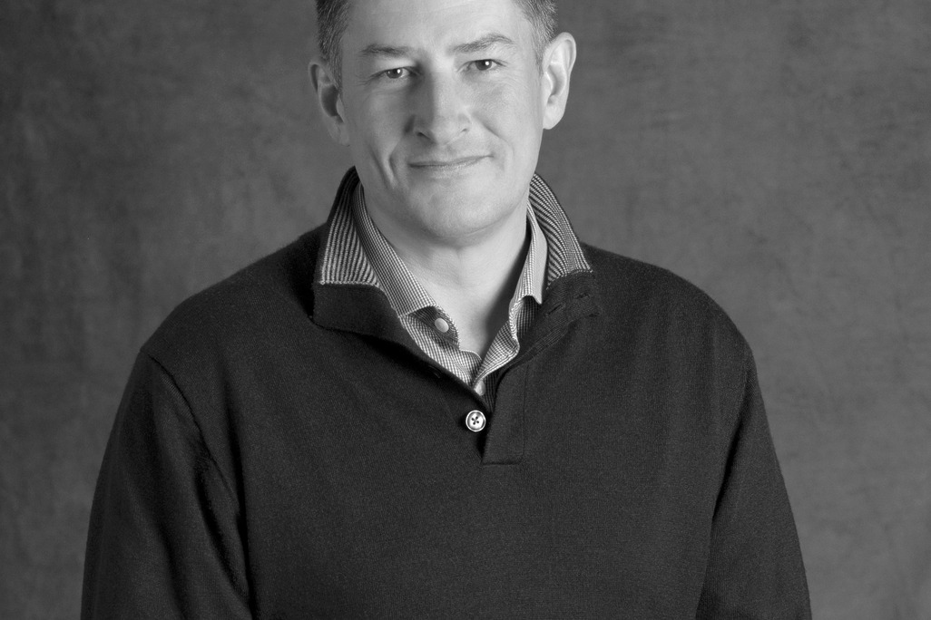 Black and white portrait of Ashley Scott, WATG, smiling against a grey backdrop.
