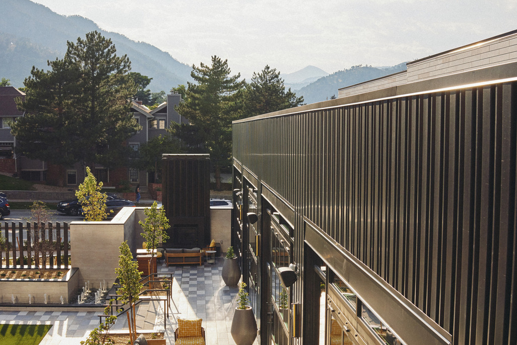 Elevated terrace with yellow woven armchairs, large ceramic planters, and panoramic views of the Boulder foothills at Limelight Hotel Boulder.