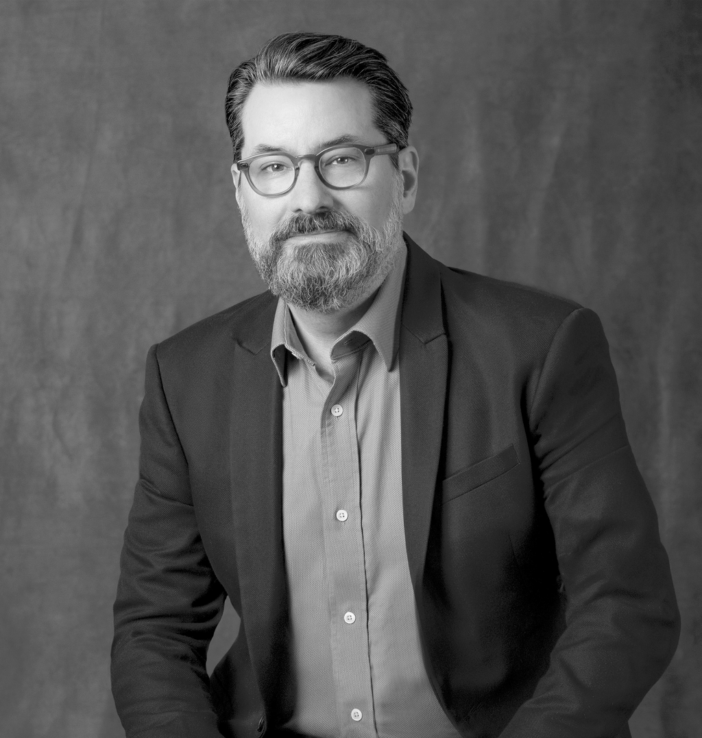 Black and white portrait of Chris Ernst, WATG, smiling against a grey backdrop.