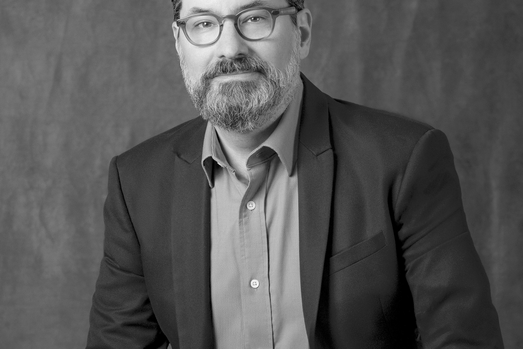 Black and white portrait of Chris Ernst, WATG, smiling against a grey backdrop.
