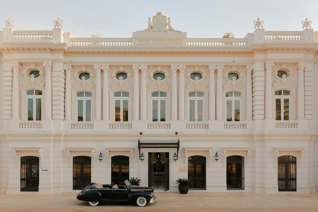 Four Seasons Hotel Cartagena facade, cream neoclassical building with ornate detailing and a vintage black convertible parked at the entrance.
