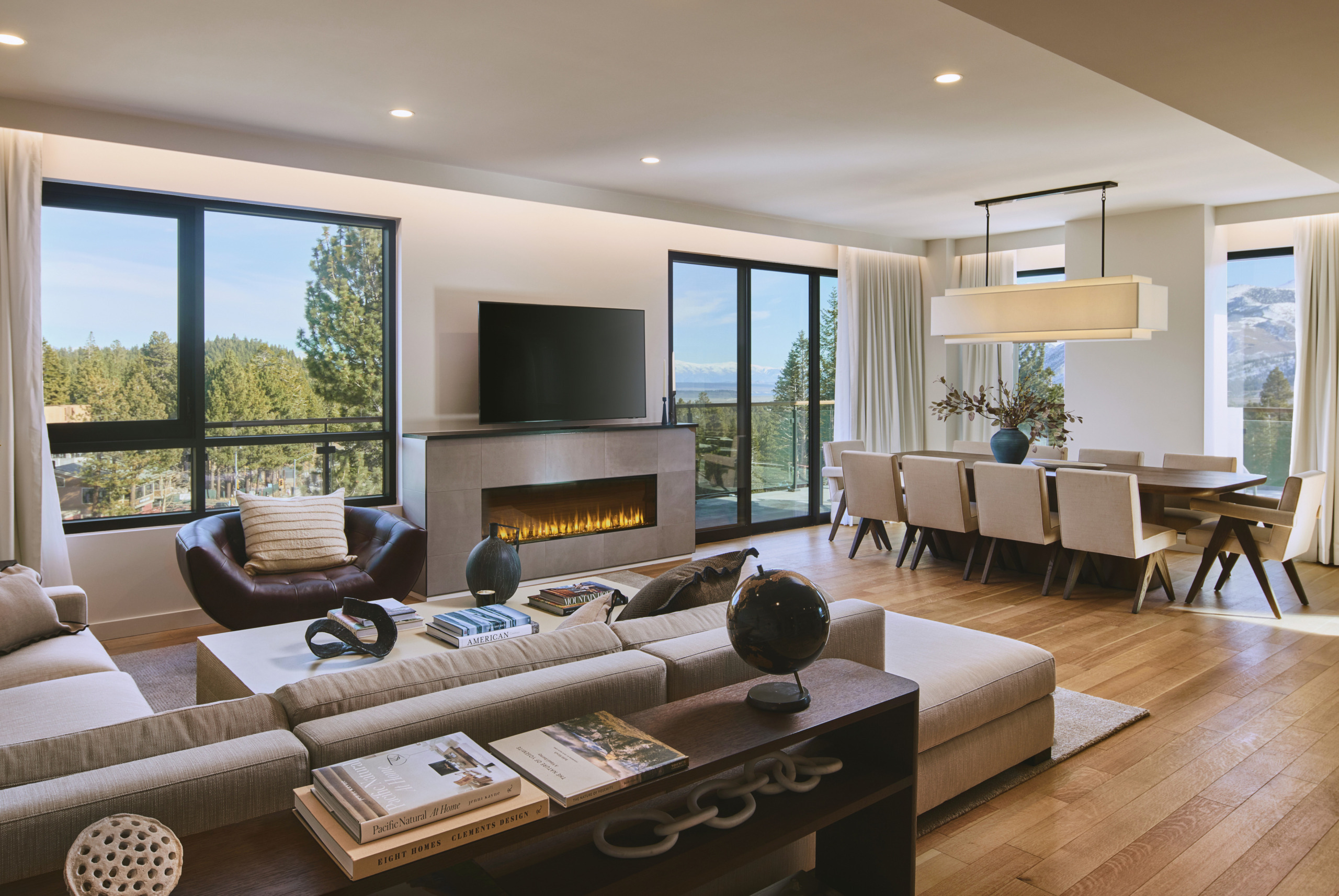 Spacious residence living area with floor-to-ceiling windows, fireplace, and views to pine forest at Limelight Hotel Mammoth Lakes, designed by WATG