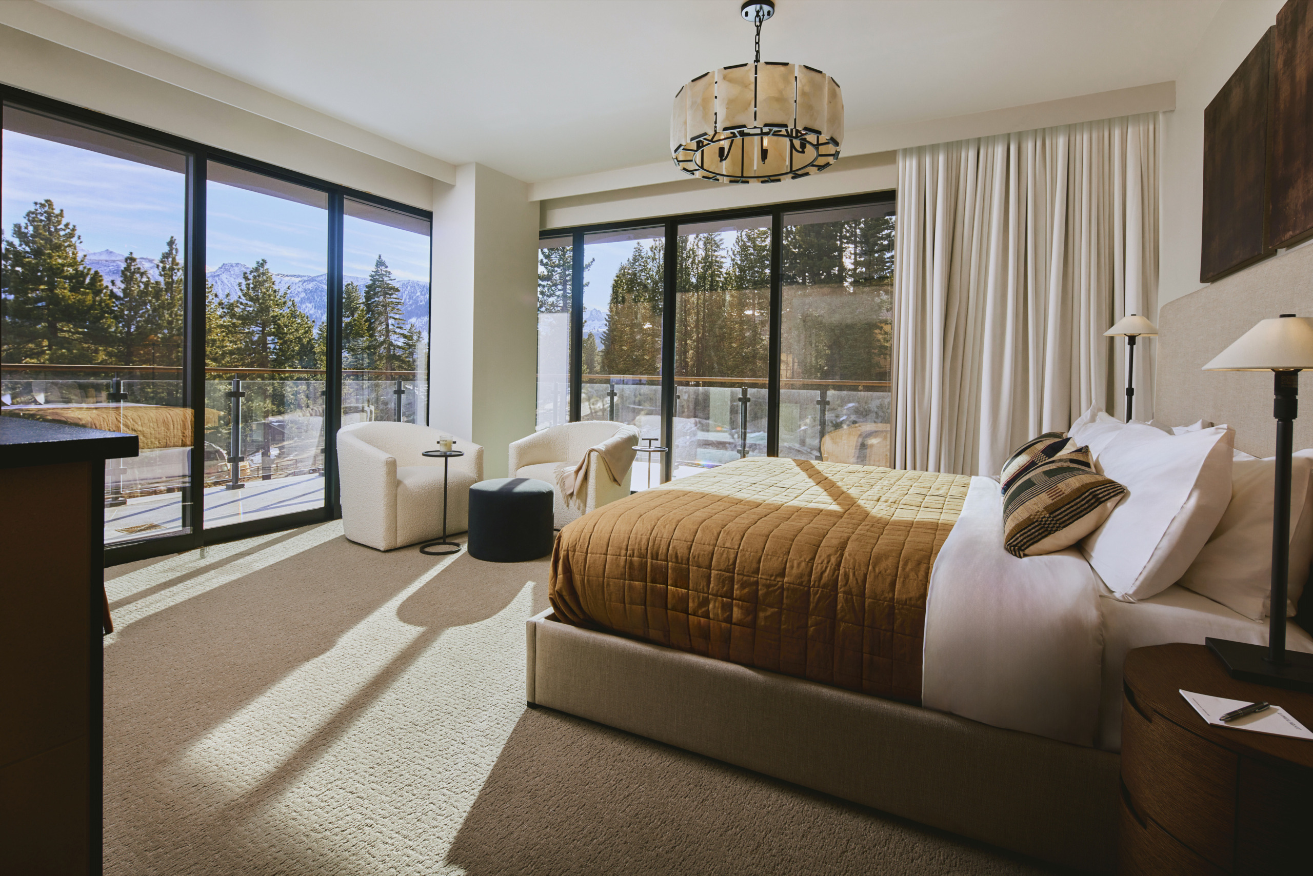 Open-plan residence interior with neutral tones, generous seating, and panoramic mountain forest views at Limelight Hotel Mammoth Lakes, designed by WATG