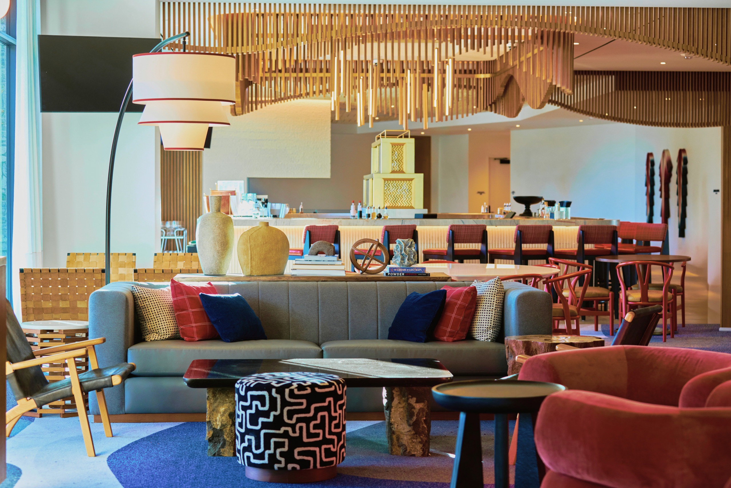 Bar and lounge with warm amber tones, patterned soft furnishings, and layered lighting at Limelight Hotel Mammoth Lakes, designed by WATG