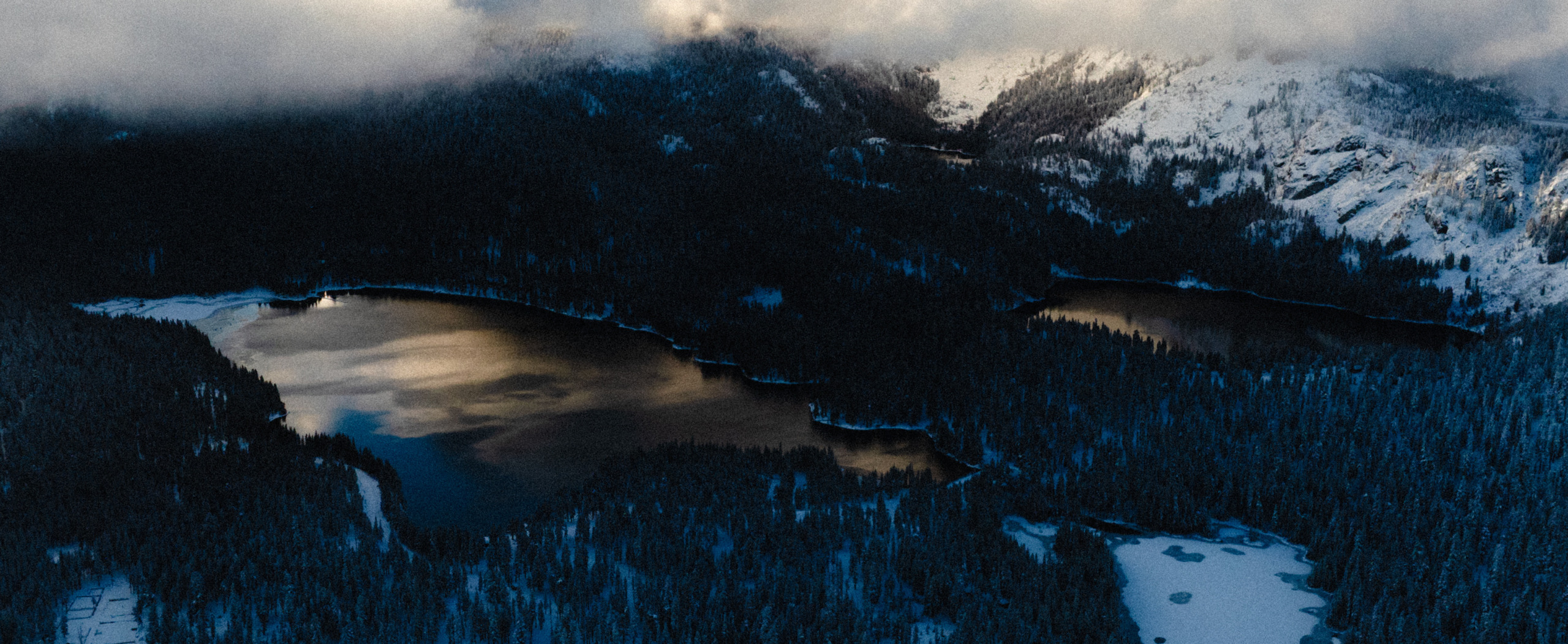 Aerial landscape view of Mammoth Lakes mountain terrain with snow-dusted peaks and pine forest at dusk, Limelight Hotel Mammoth Lakes by WATG