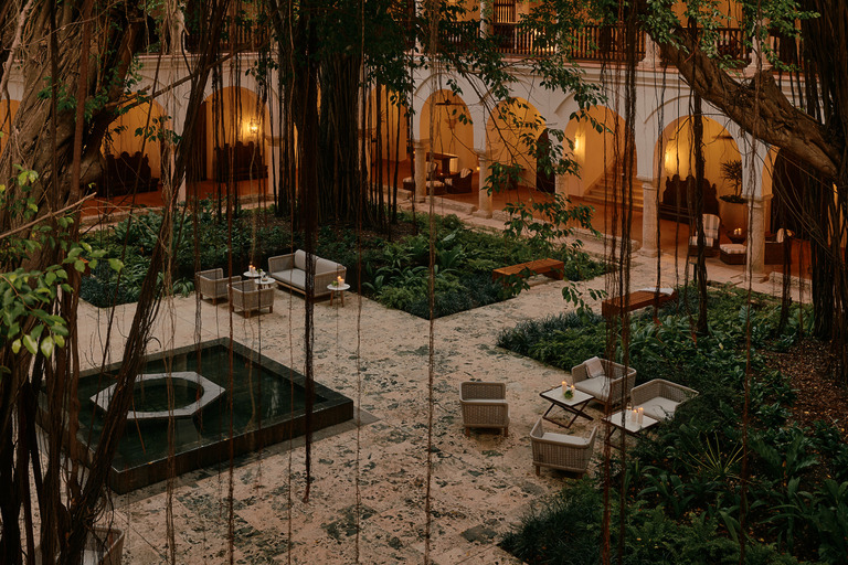 Candlelit courtyard at Four Seasons Hotel Cartagena with tropical trees, a reflecting pool and arched colonnades