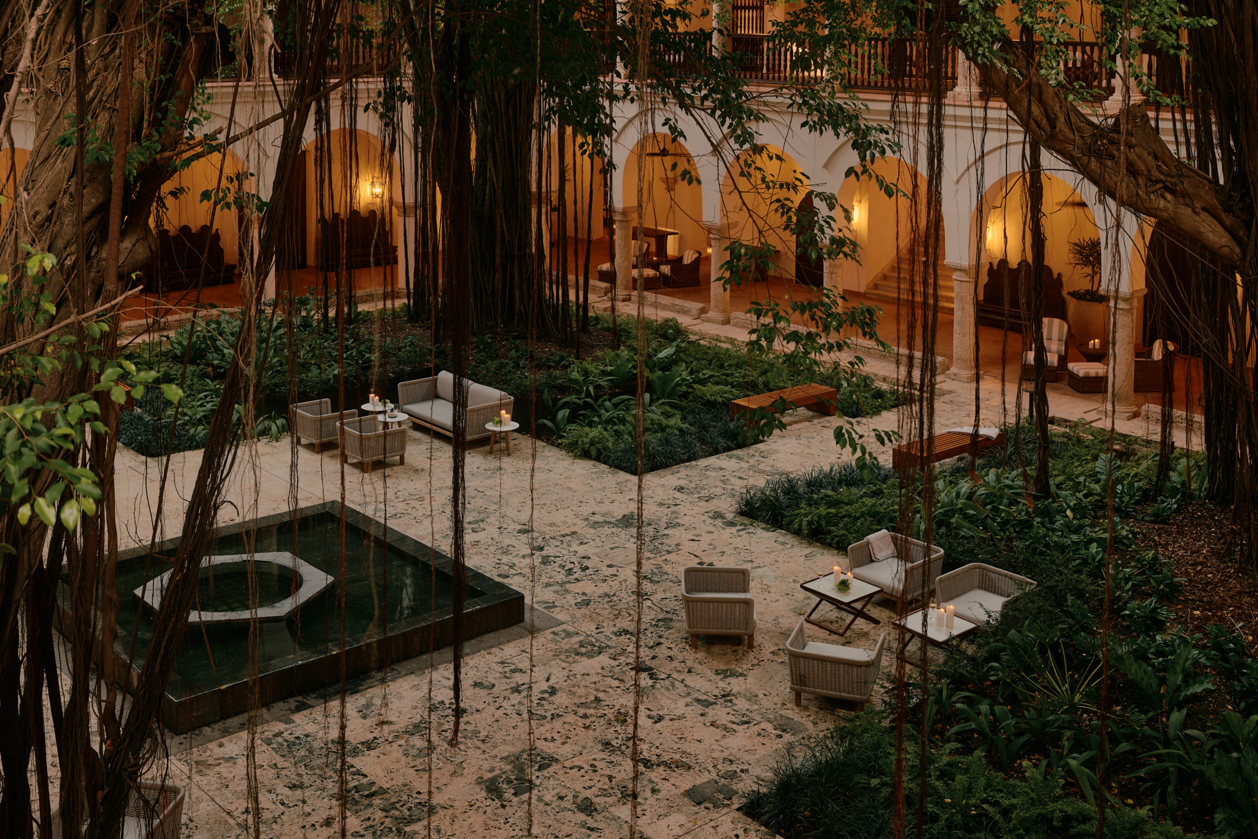 Candlelit courtyard at Four Seasons Hotel Cartagena with tropical trees, a reflecting pool and arched colonnades