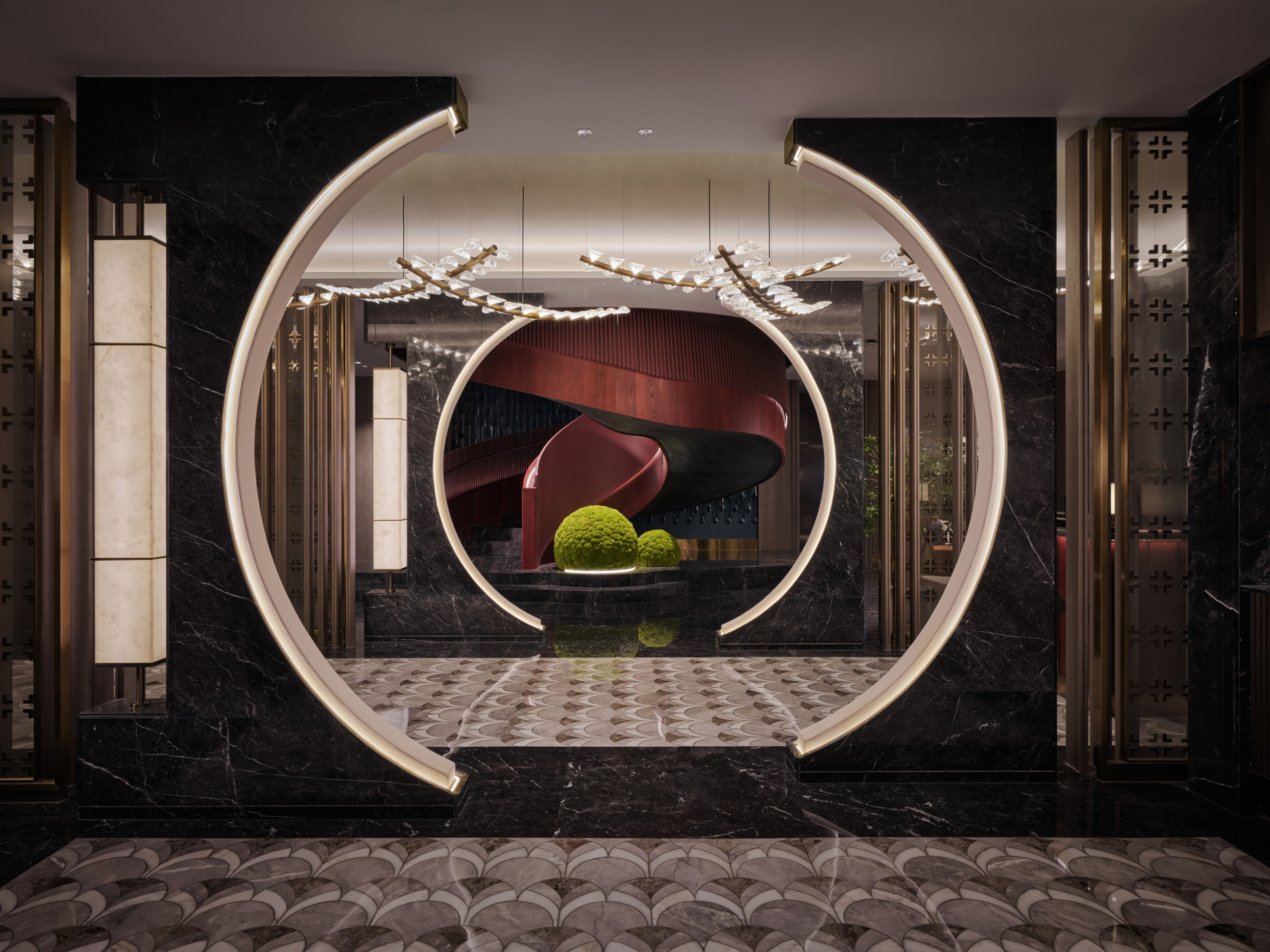HUALUXE Zhongshan moon gate entrance framed in dark marble with a sculptural red staircase beyond.