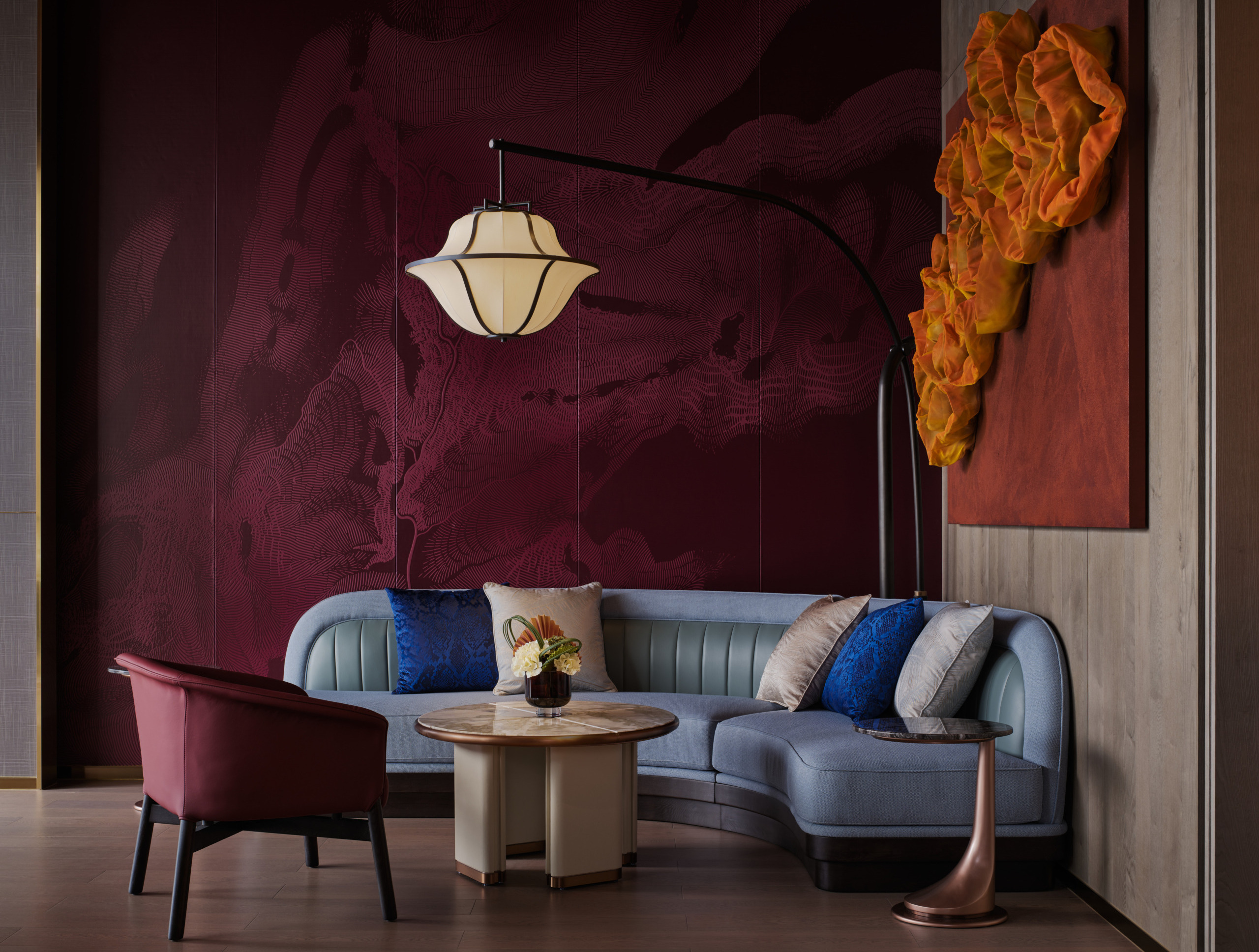 HUALUXE Zhongshan lounge seating area with curved blue sofa, lantern floor lamp and deep crimson feature wall.
