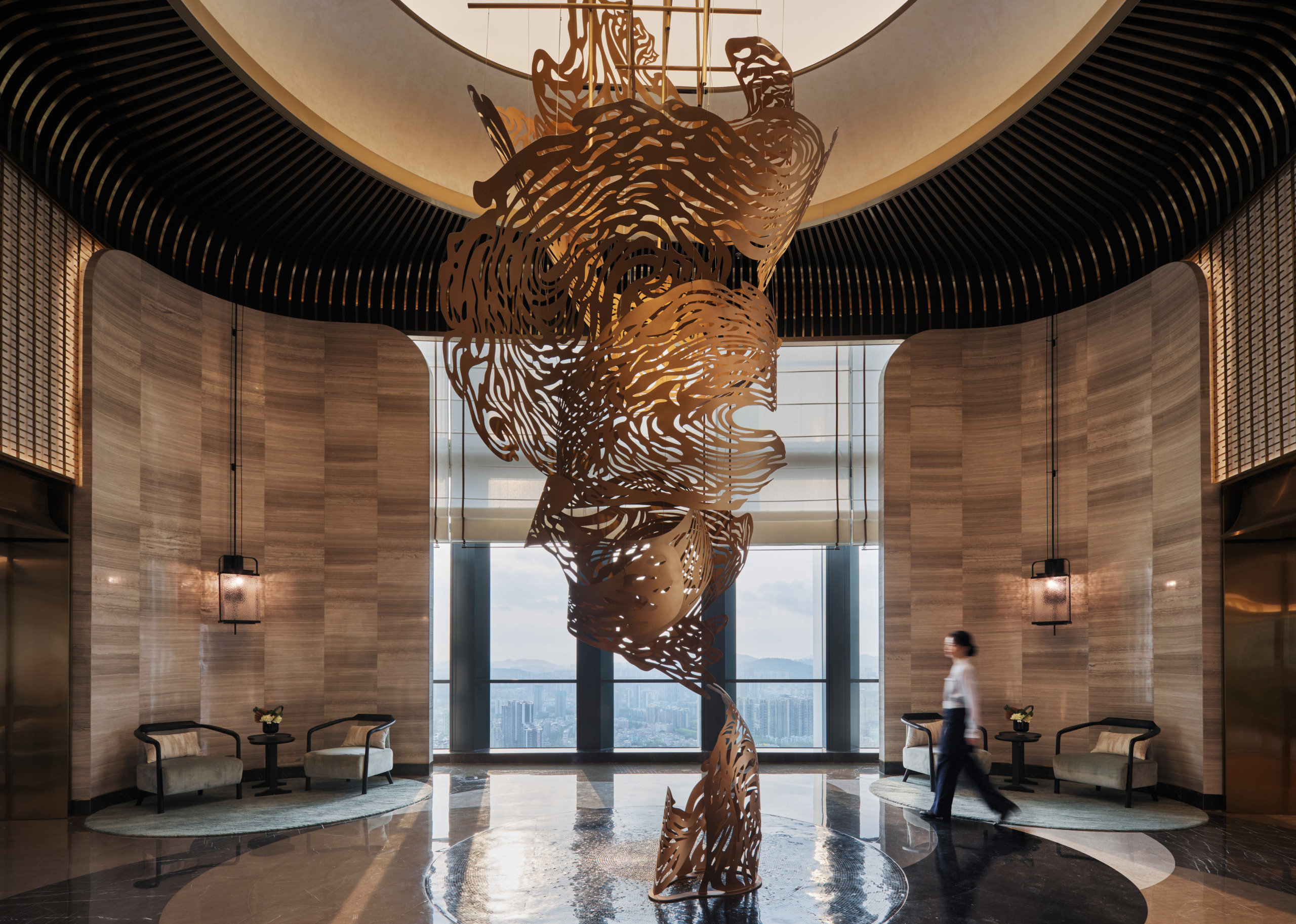 HUALUXE Zhongshan hotel lobby with a towering bronze sculptural installation suspended beneath a circular ceiling.