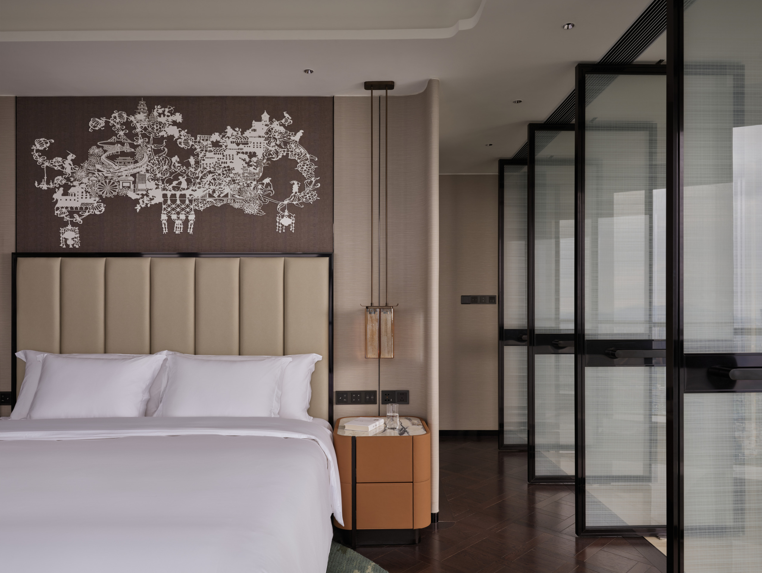 HUALUXE Zhongshan guest room with upholstered headboard, paper-cut artwork above the bed and glazed partition wall.