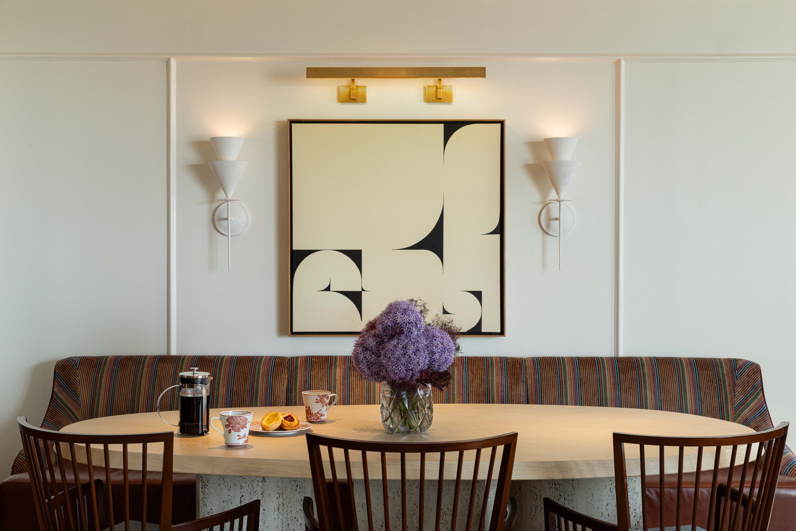 Dining nook with striped banquette, oval table, and abstract black-and-cream artwork, Promenade Suite, JW Marriott Essex House.