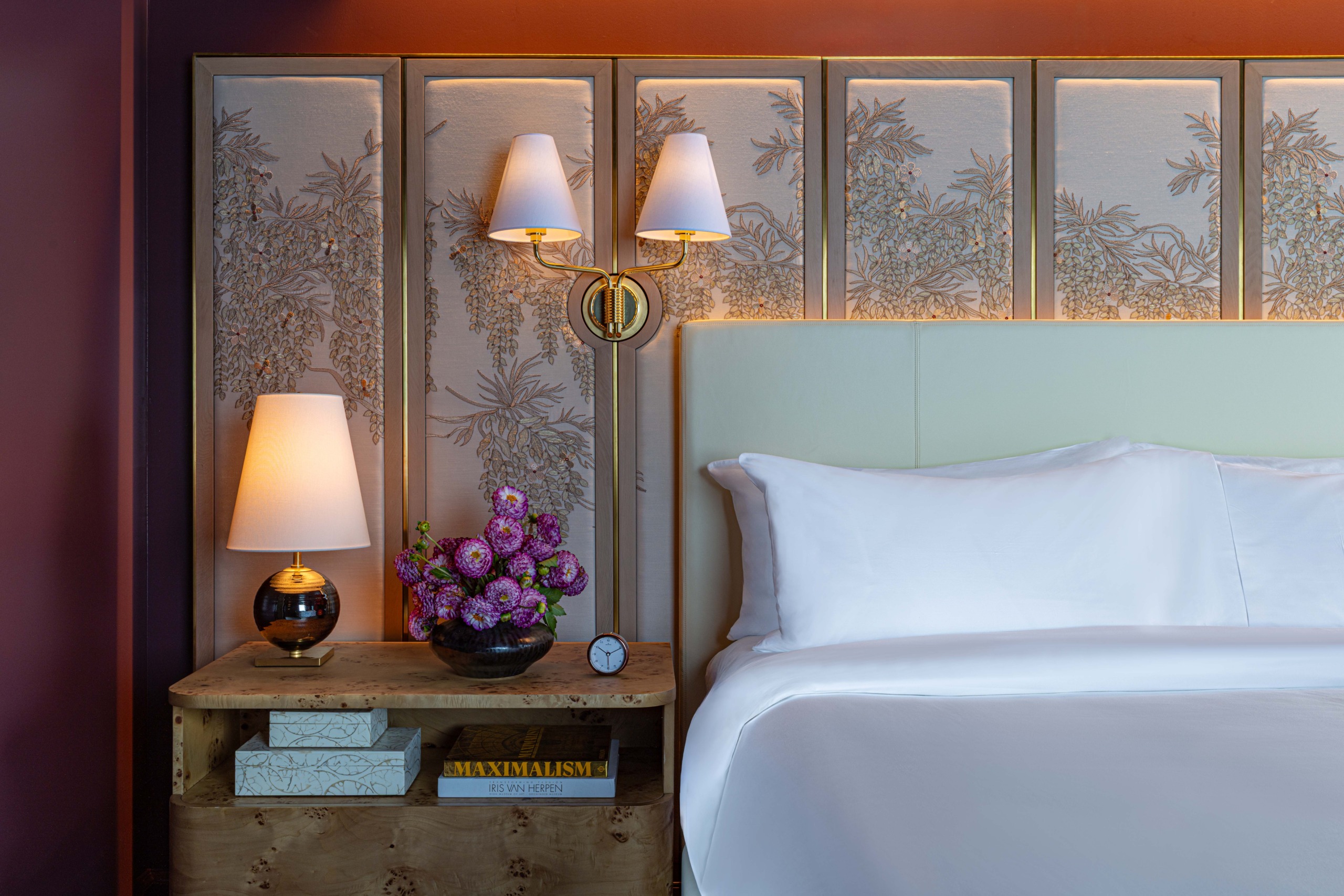 Burl wood nightstand with brass sconce and botanical wallcovering panel beside mint-green upholstered headboard, JW Marriott Essex House Promenade Suite king guestroom
