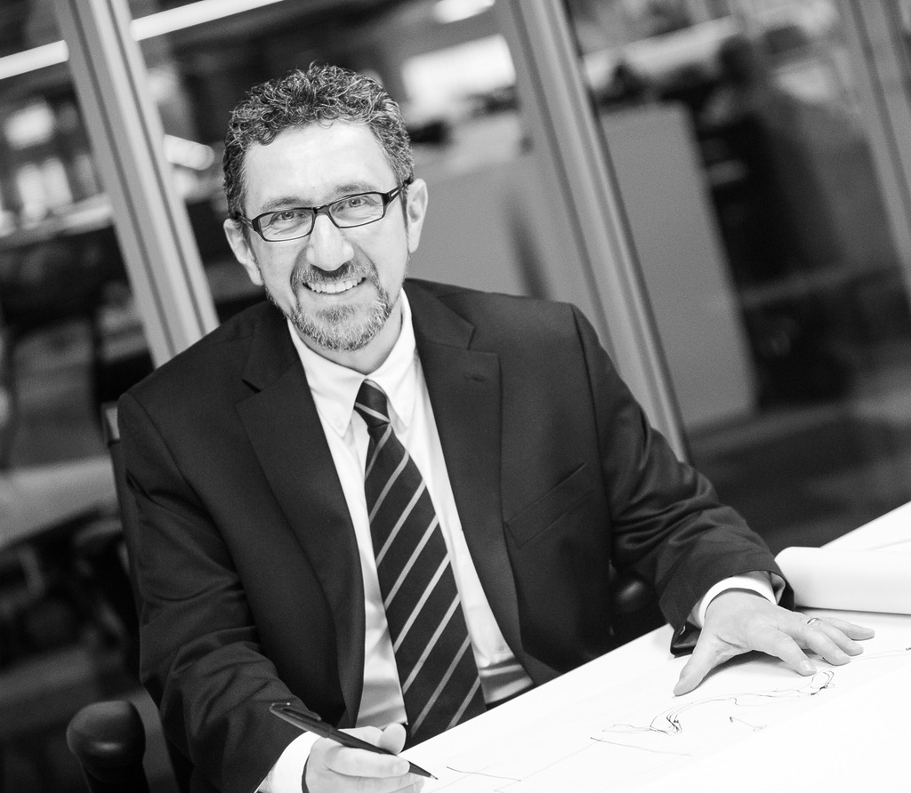 Black and white photo of Ala Hanson, Associate Principal and Regional Director of WATG Abu Dhabi, dressed in a suit with an office backdrop.