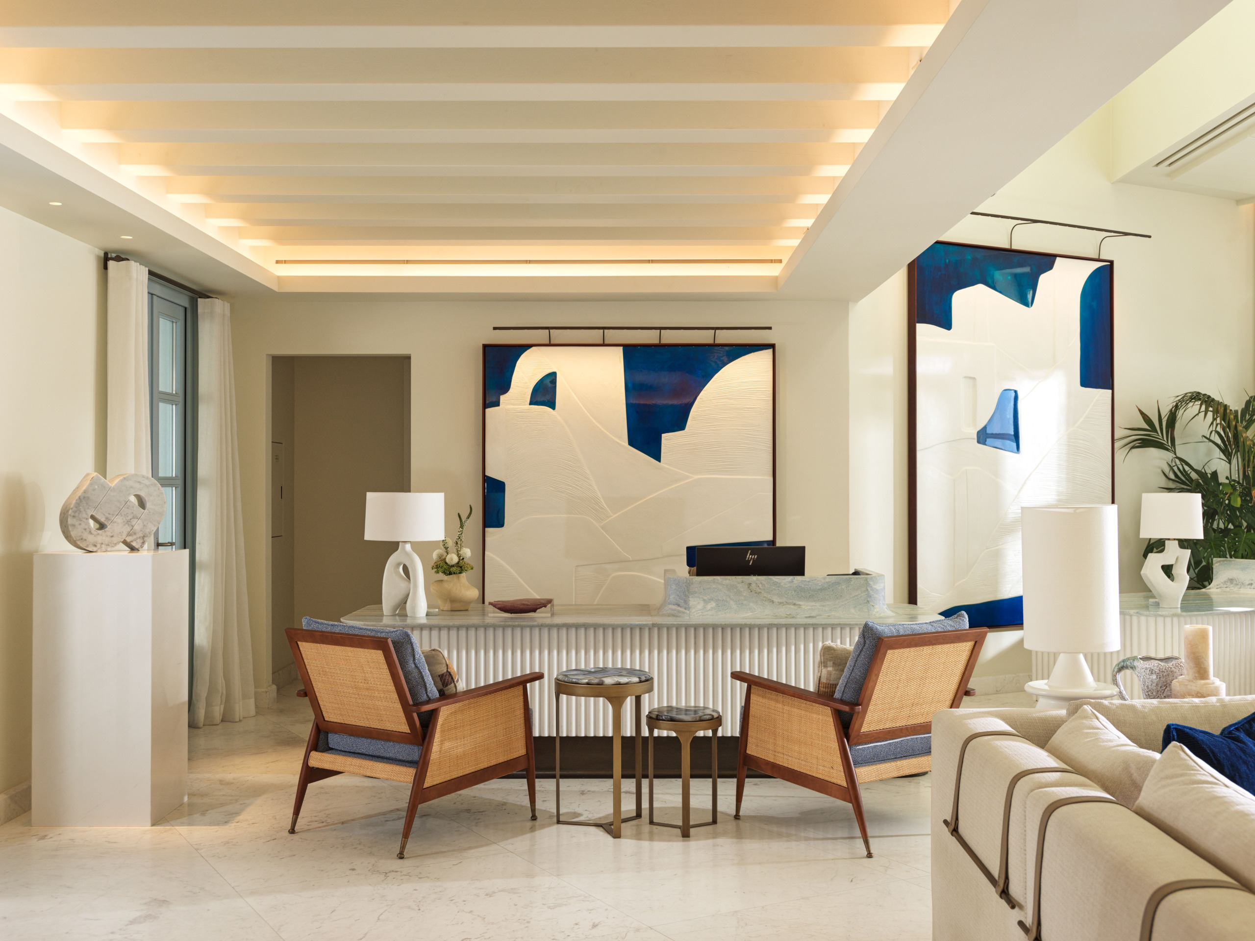 Reception at Four Seasons Mykonos: fluted marble-topped desk, cane armchairs and blue-and-white artworks of island houses.