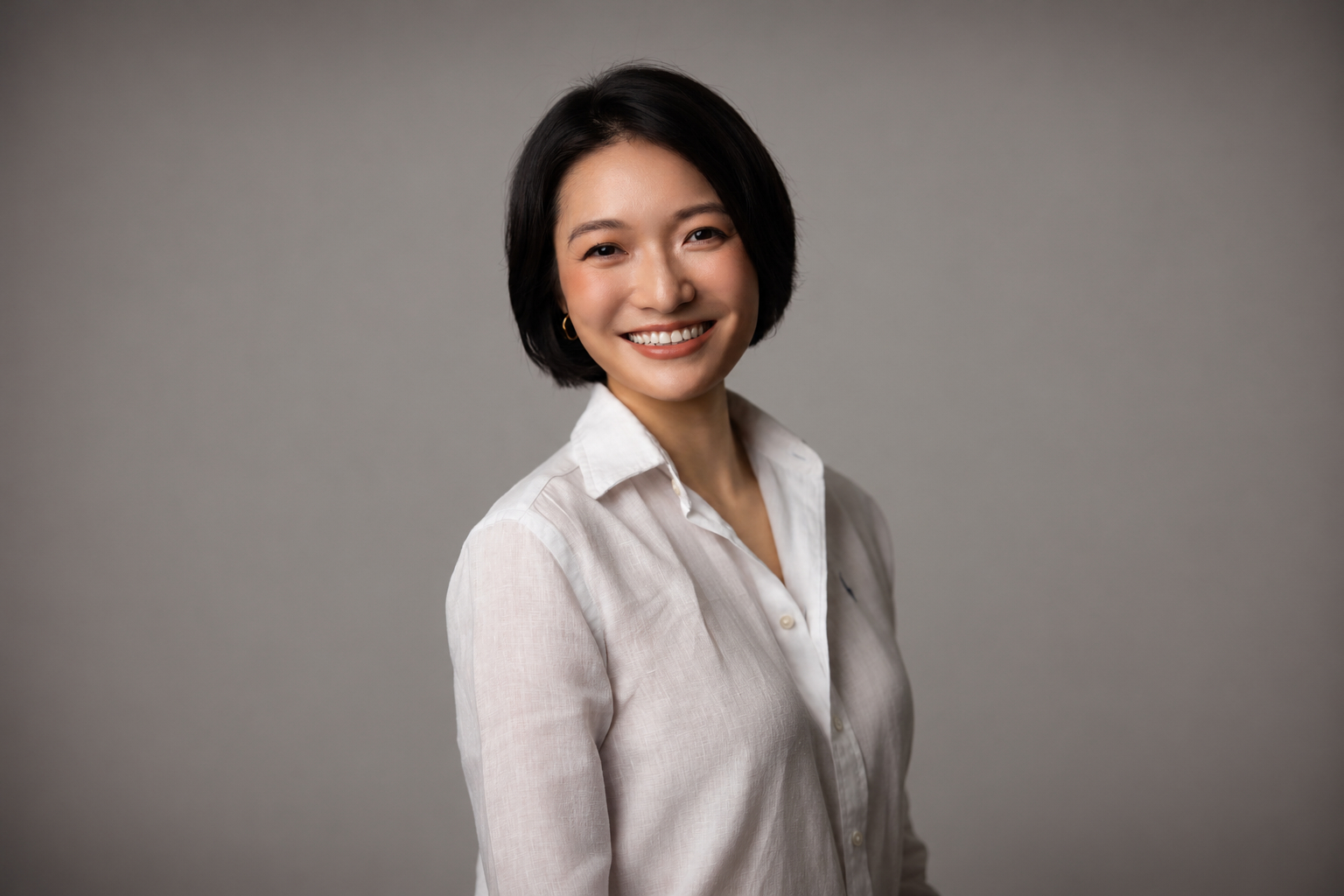 Headshot of Cara Ding, smiling against a grey background.